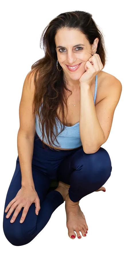 A smiling woman sitting cross-legged on a yoga mat
