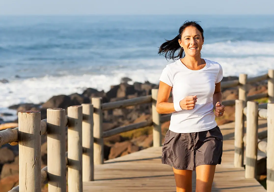 A woman running along a boardwalk beside the sea