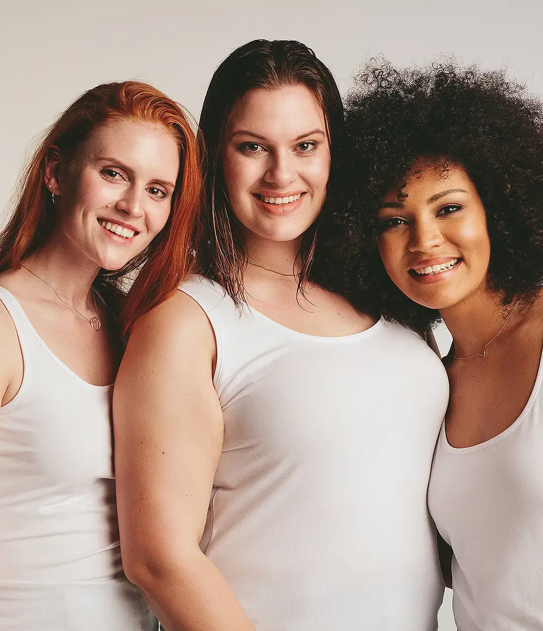 Three women standing arm in arm, smiling