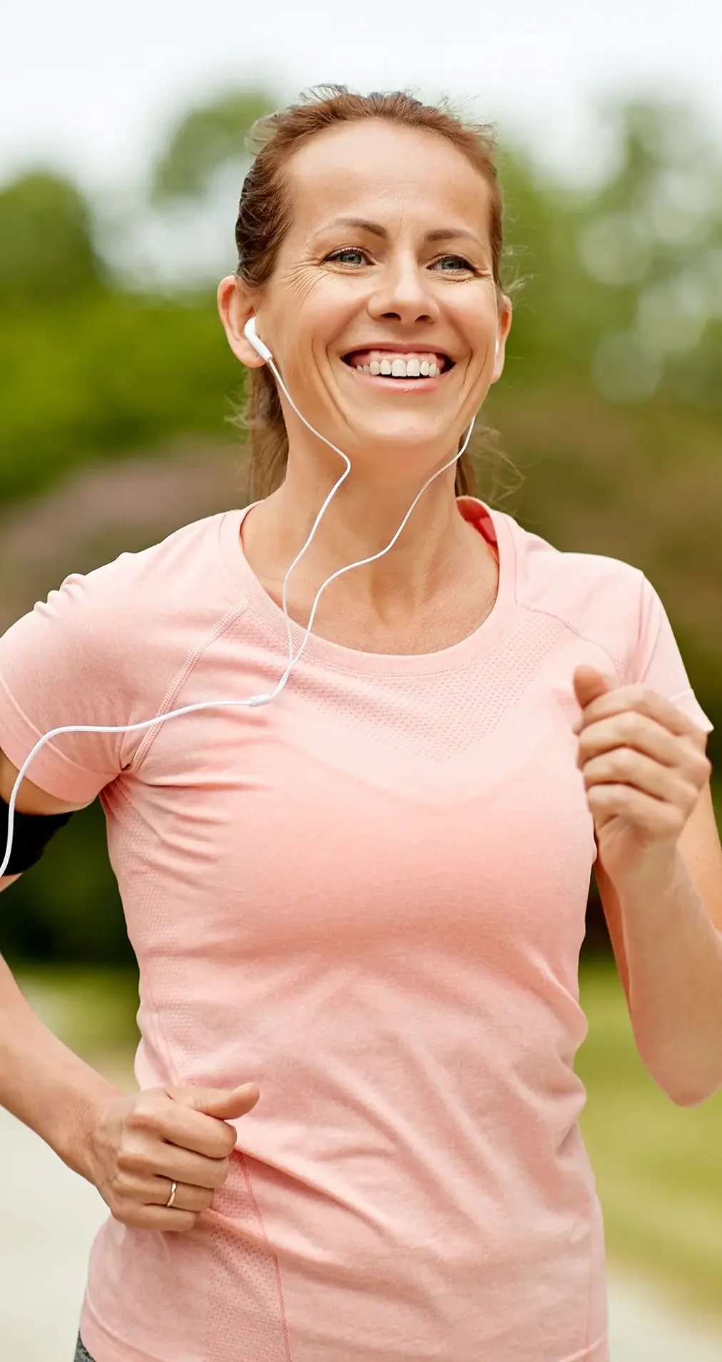 A smiling woman out for a run, wearing earphones