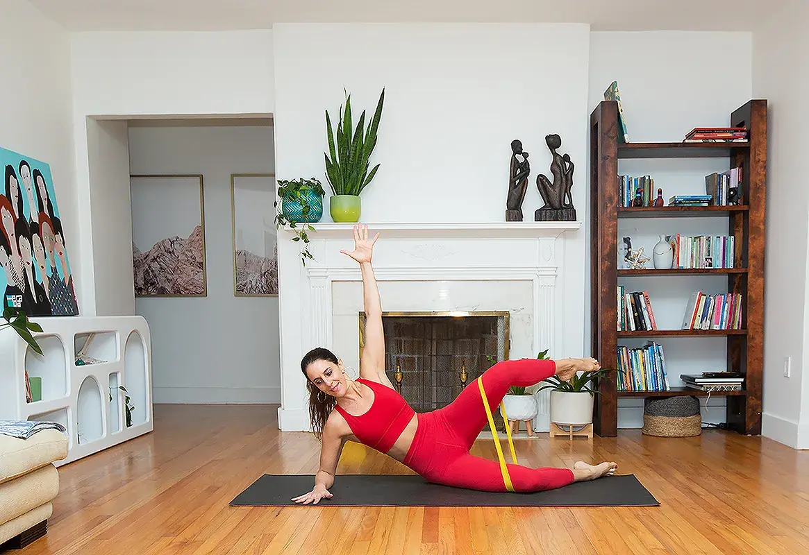 A woman holding her baby while exercising on a mat
