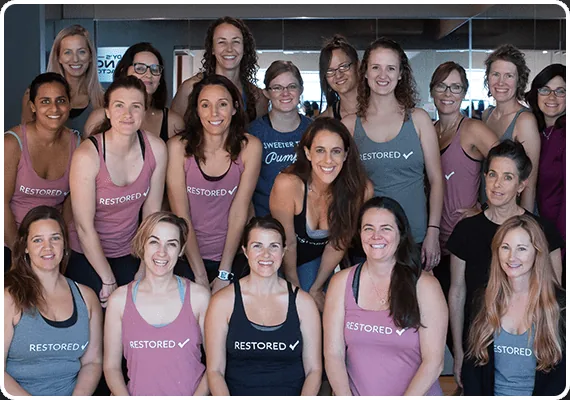 A group of smiling RYC® members wearing RESTORED tank tops